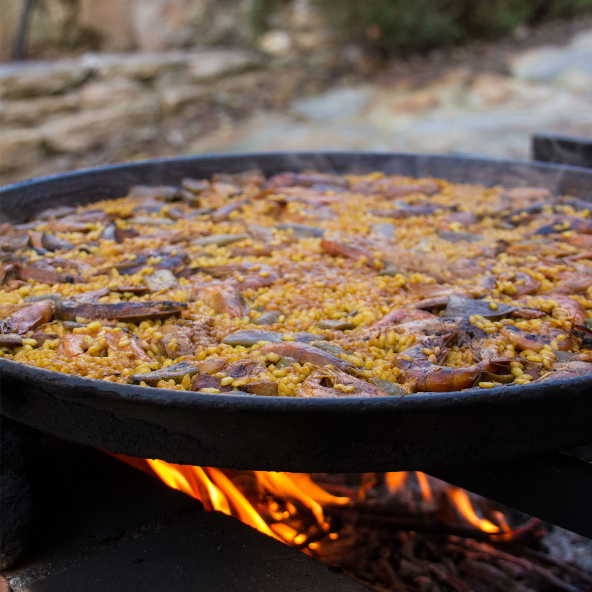 Spanish,Paella,Cooked,On,Natural,Log,Fire,And,Coal,In Spanish Paella cooked on natural log fire and coal in a traditional fireplace.